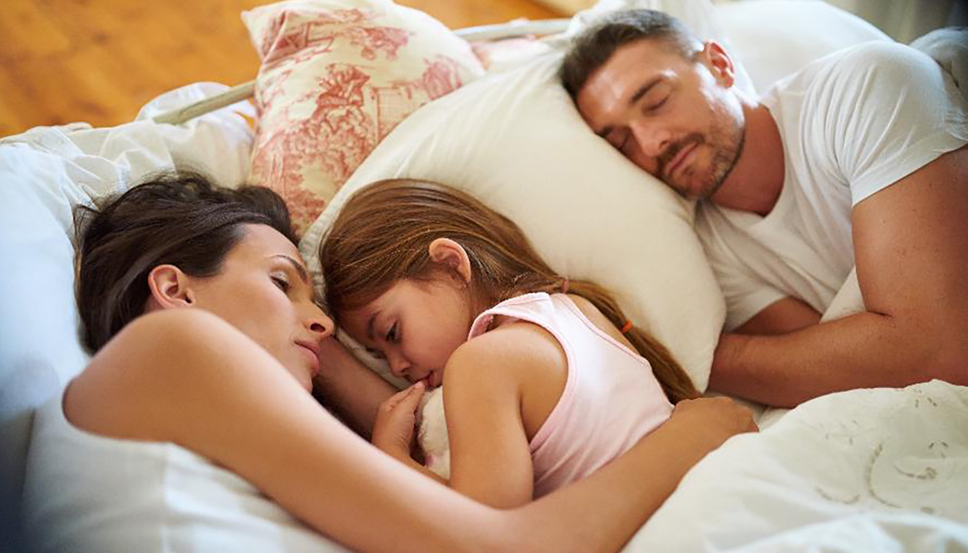 Menina dormindo na cama dos pais. Isso pode ser tratado com microfisioterapia Sorocaba.